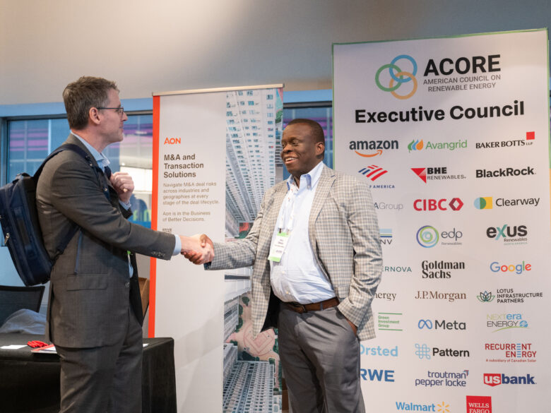 Two attendees shaking hands at the ACORE Finance Forum.