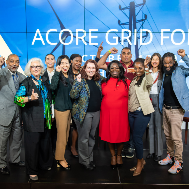 Accelerate members smiling and cheering for the camera on stage at the ACORE Grid Forum