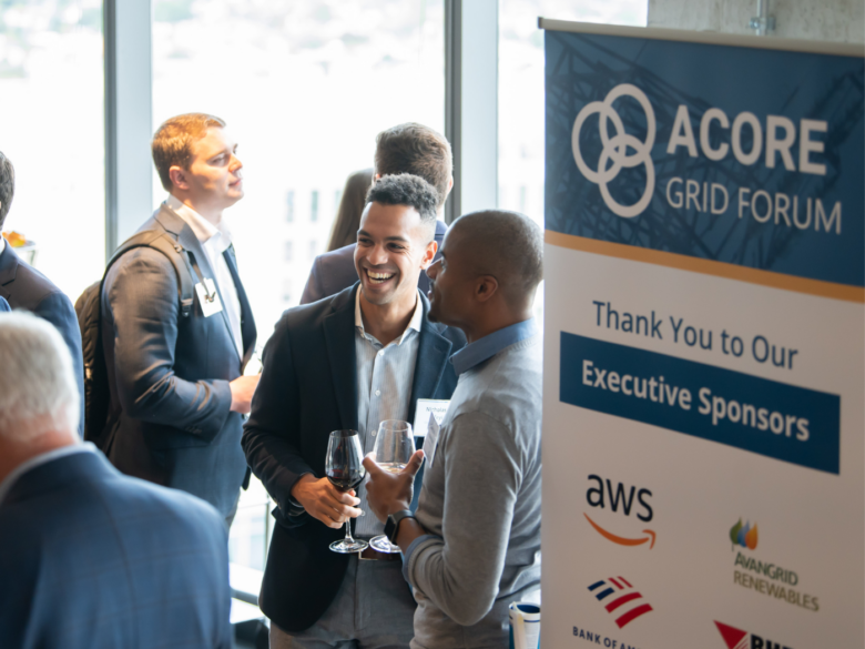 ACORE Grid Forum attendees networking and standing next to an executive sponsor sign.