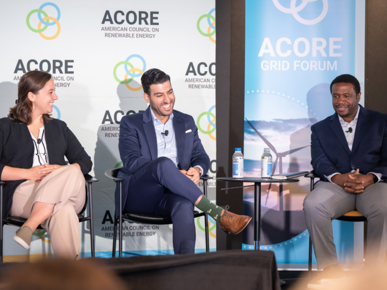 Three panelists sitting on stage and smiling at one another.