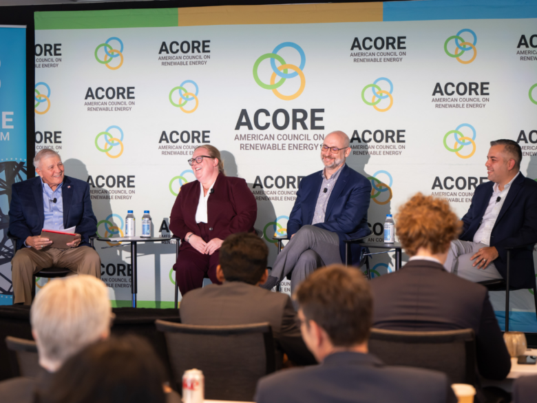 Four panelists sitting on stage and smiling at one another.