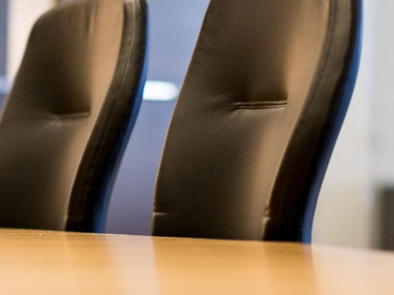 Several empty black leather office chairs around a board table.