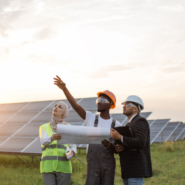 Three construction workers looking at solar panels at sunset.