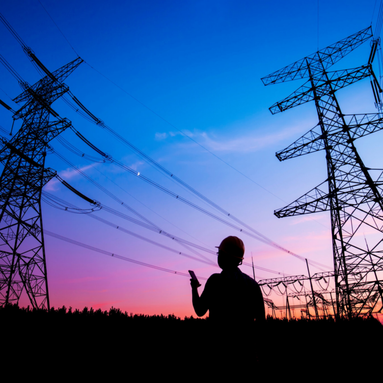 A transmission worker looks up at the night sky and transmission lines above him