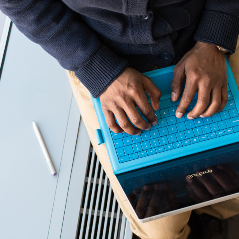 A person typing on a blue laptop.