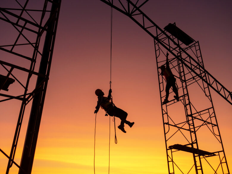 Male working on a construction site silhouetted against a sunset sky