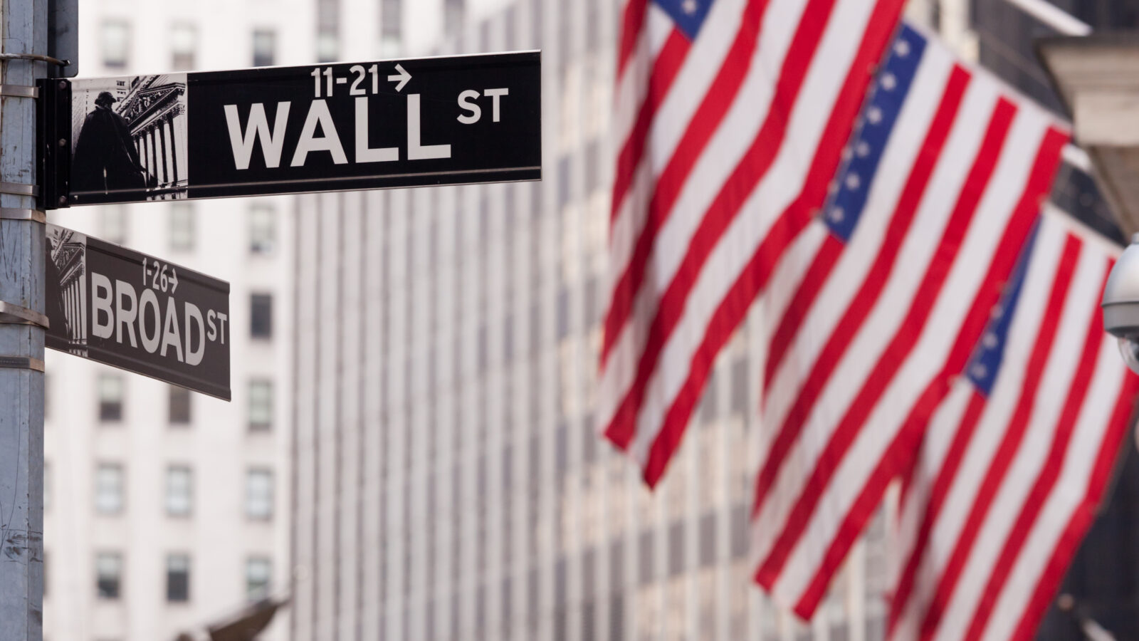The Signage on Wall Street in the Financial District of New York City with American Flags in the background.