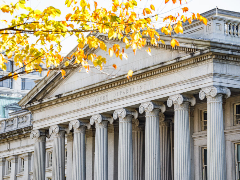 Exterior of the the U.S. Treasury building with yellow fall leaves in front