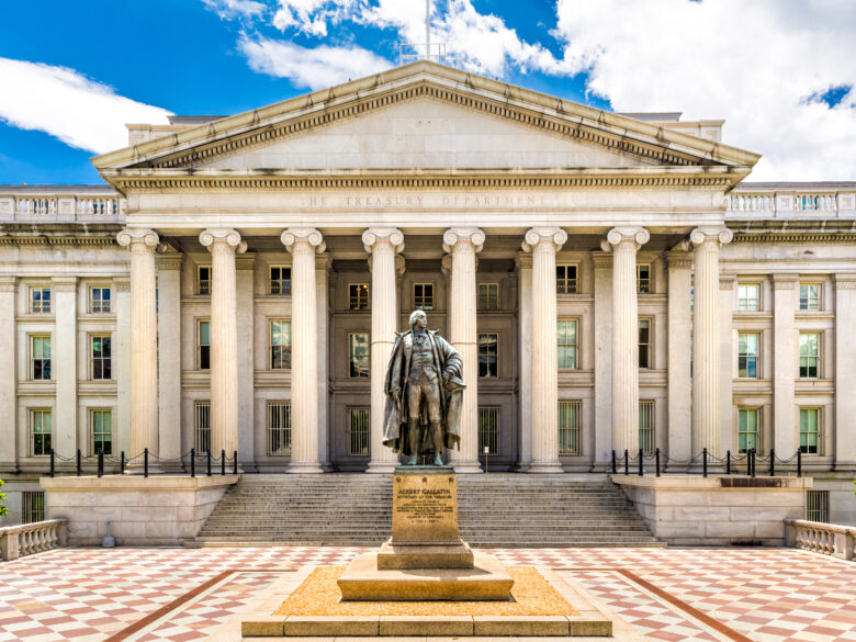 U.S. Treasury building with ornate white columns and a statue of Alexander Hamilton out front