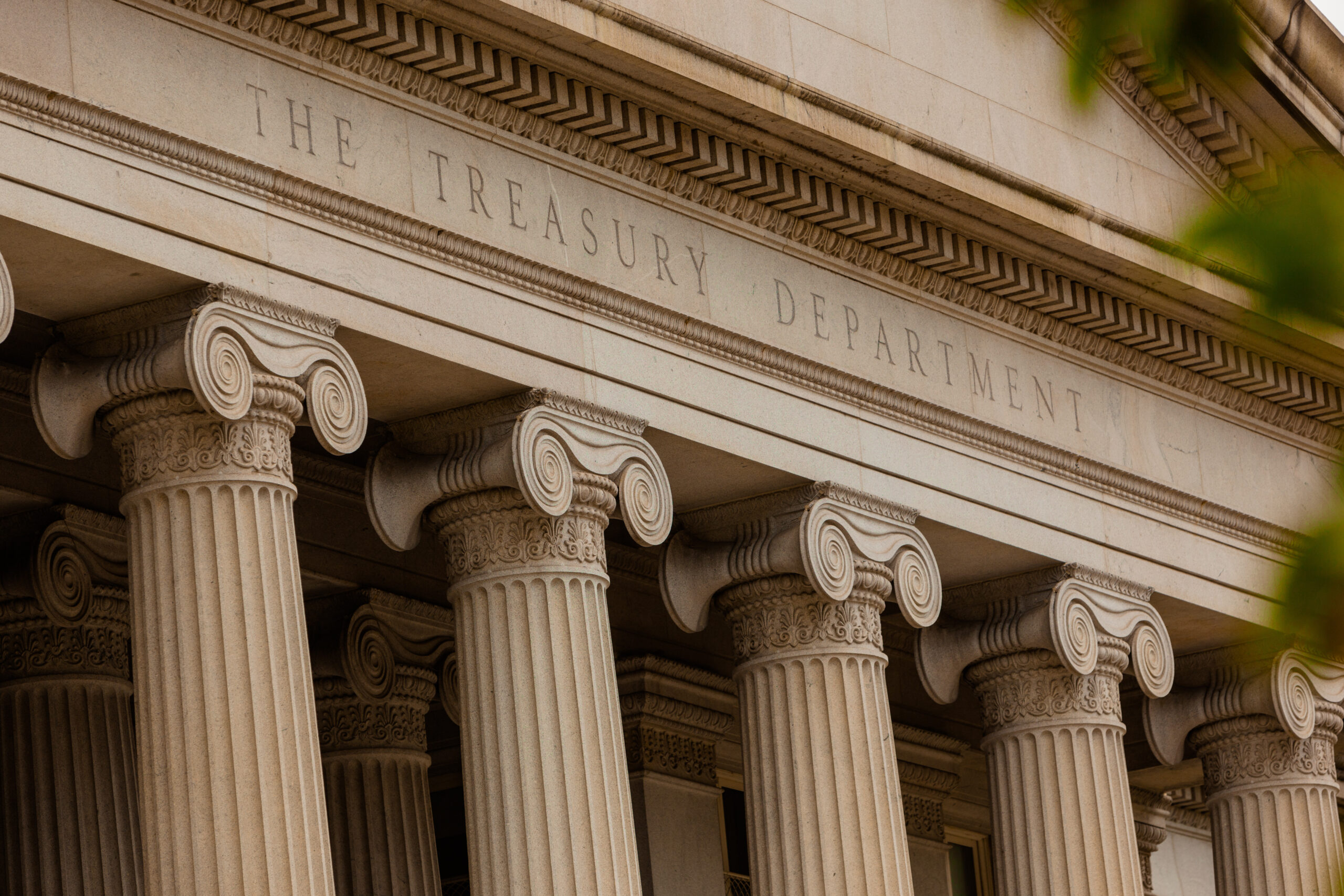 Exterior of US Treasury building with columns and text reading "The Treasury Department"