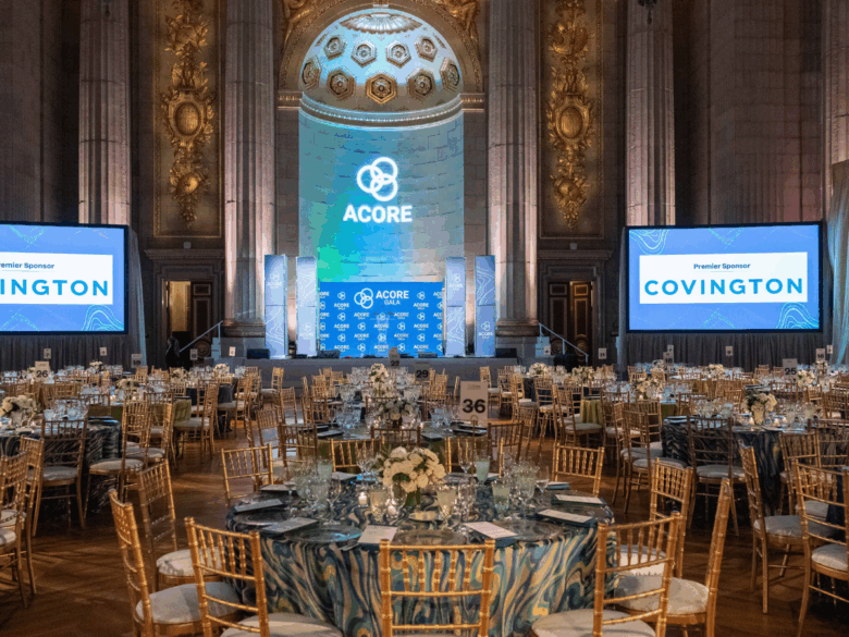 Room shot of the 2025 ACORE Gala at the Mellon Auditorium featuring set tables, screens, and the main stage.