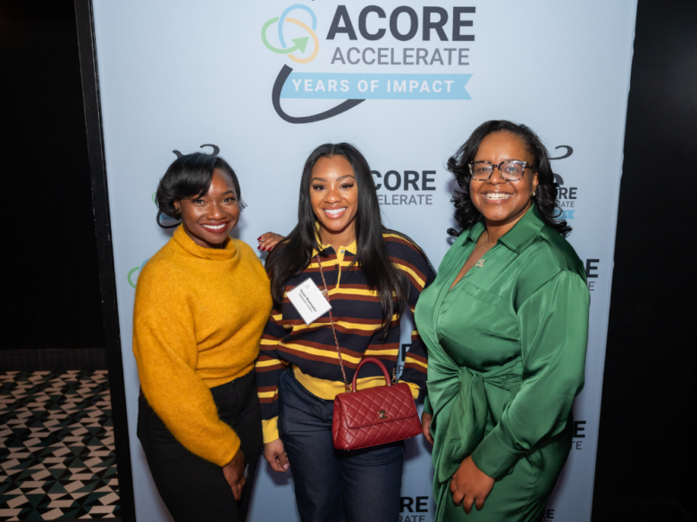 Three attendees smile for a photo at the photobooth at the 2026 Accelerate 5th Anniversary Reception.
