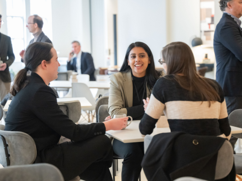 Attendees sit at a table networking.