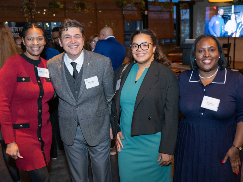 Four ACORE Accelerate reception attendees smile for a group photo.