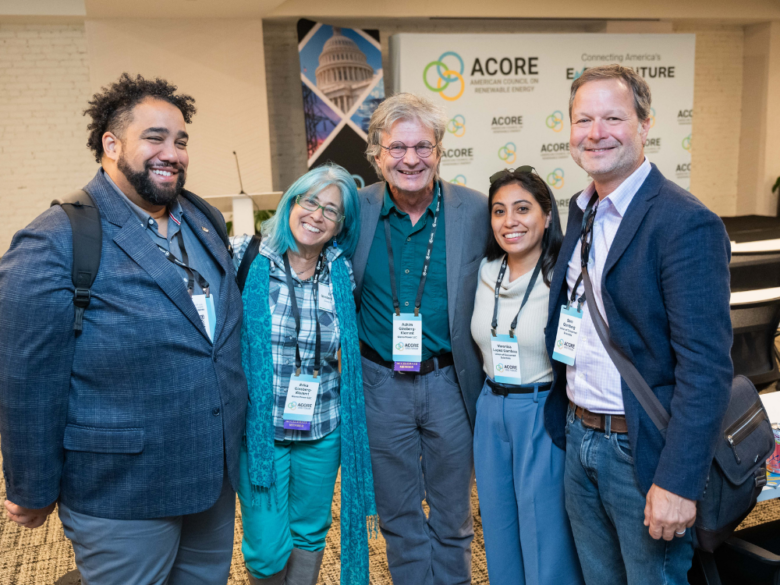 Five attendees smile for a group photo at the 2025 ACORE Grid Forum.
