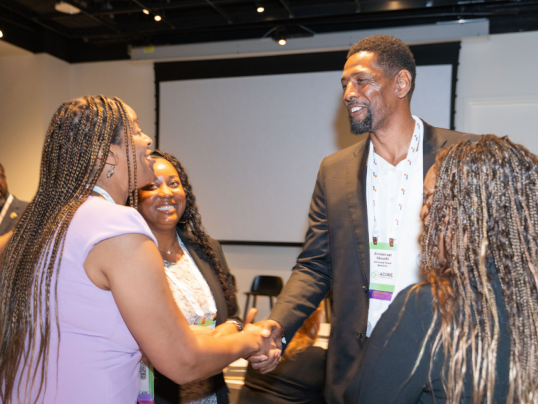Two attendees smile and shake hands while networking at the Accelerate Forum.