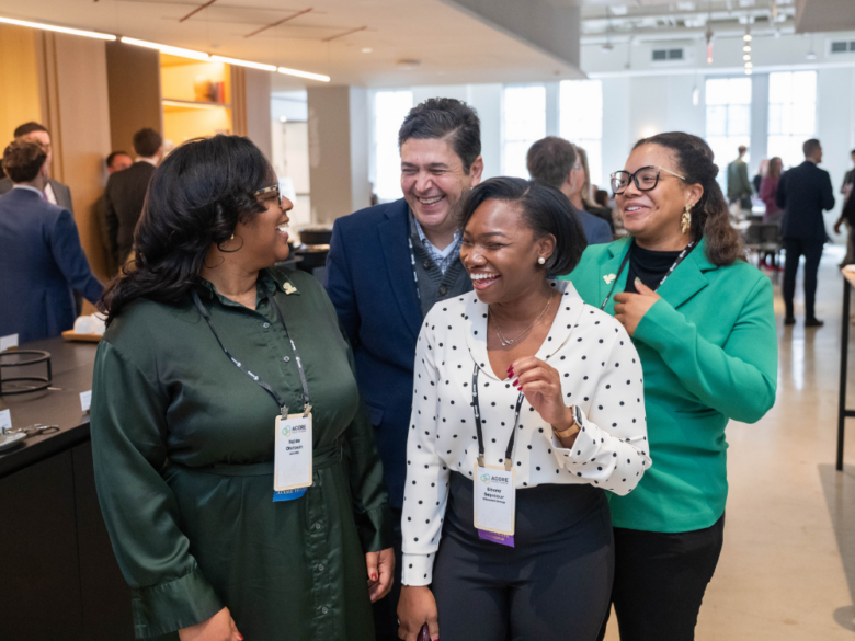 Four event attendees smiling and laughing together during a networking break.