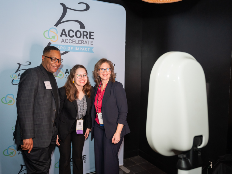 Three event attendees smiling and posing together for a photo booth picture.