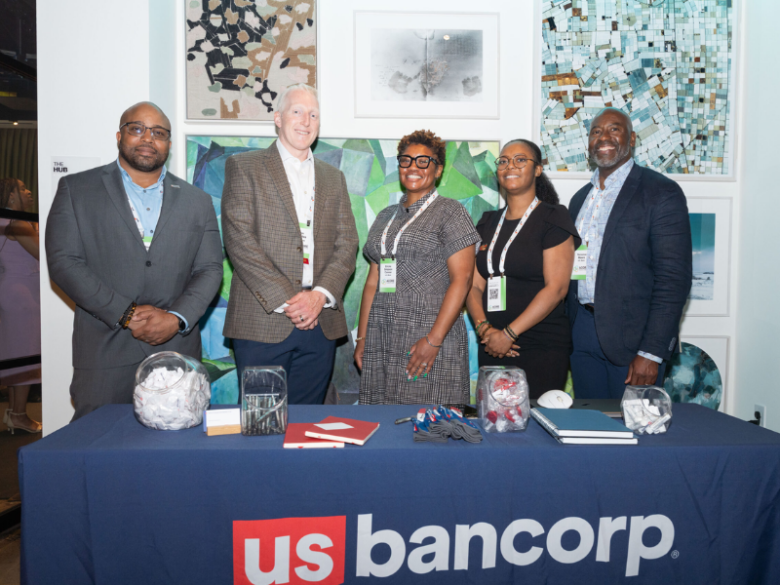 Five US Bank team members smile behind their sponsor booth.