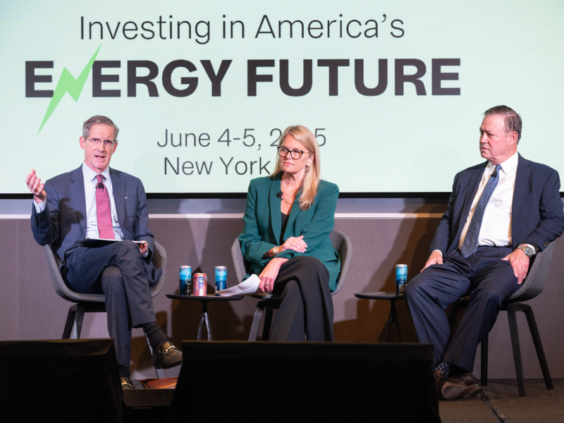 Three ACORE Finance Forum speakers sit on stage and address attendees.