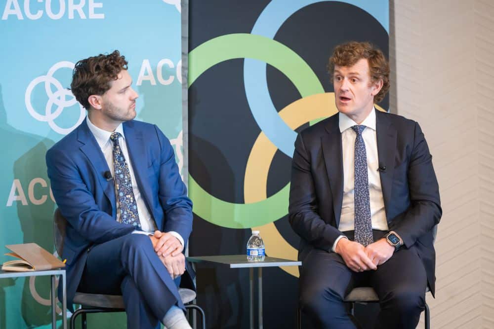 Two panelists sits on stage and addresses attendees at the ACORE Policy Forum.