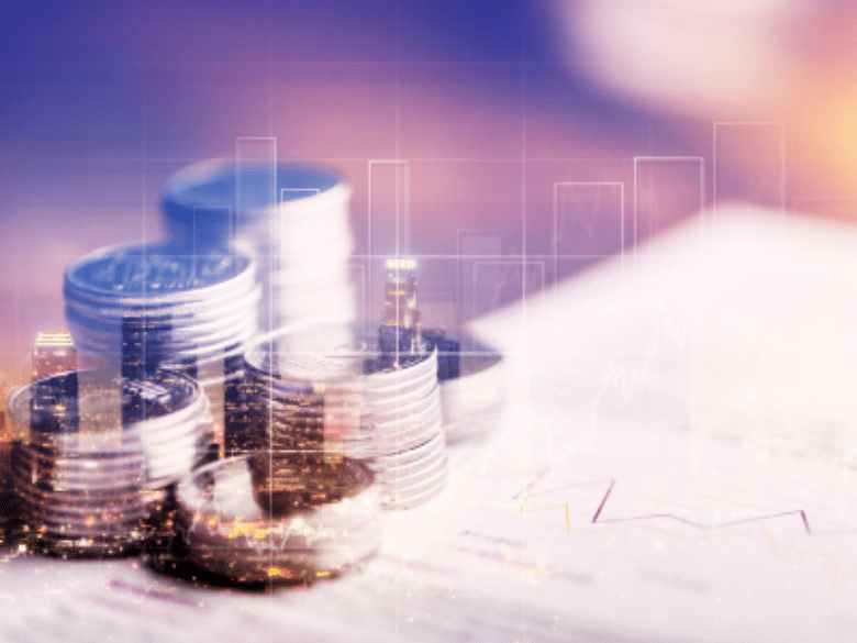 Stacked columns of coins on a financial document with faint line charts and city lights overlaid, symbolizing economic growth, investment, and financial analysis