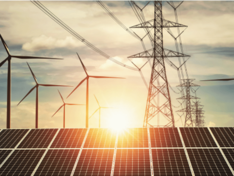Solar panels, wind turbines, and transmission lines at sunset.