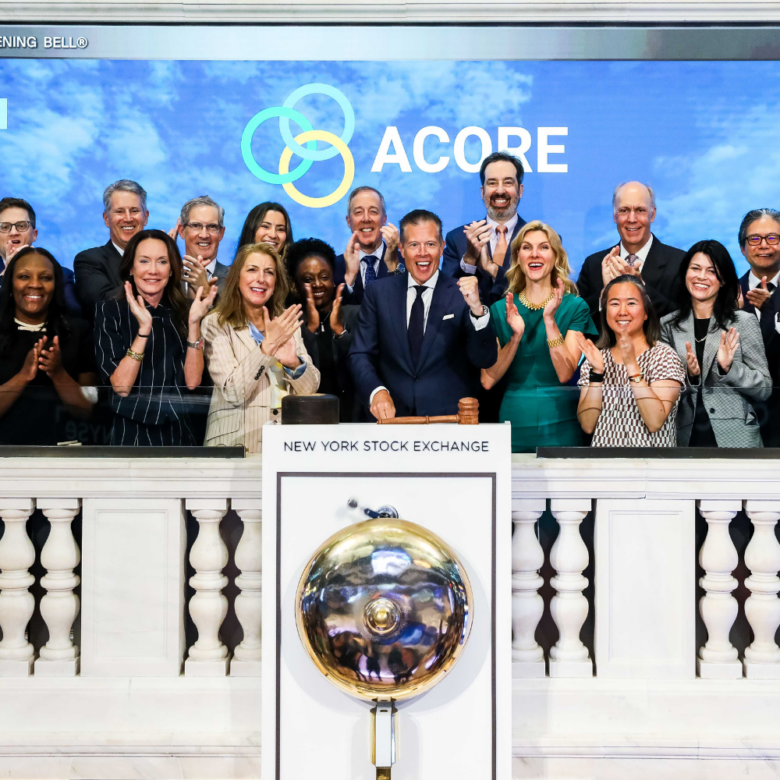 A group of ACORE team and board members applaud behind the ceremonial bell podium at the New York Stock Exchange after ringing the Opening Bell.