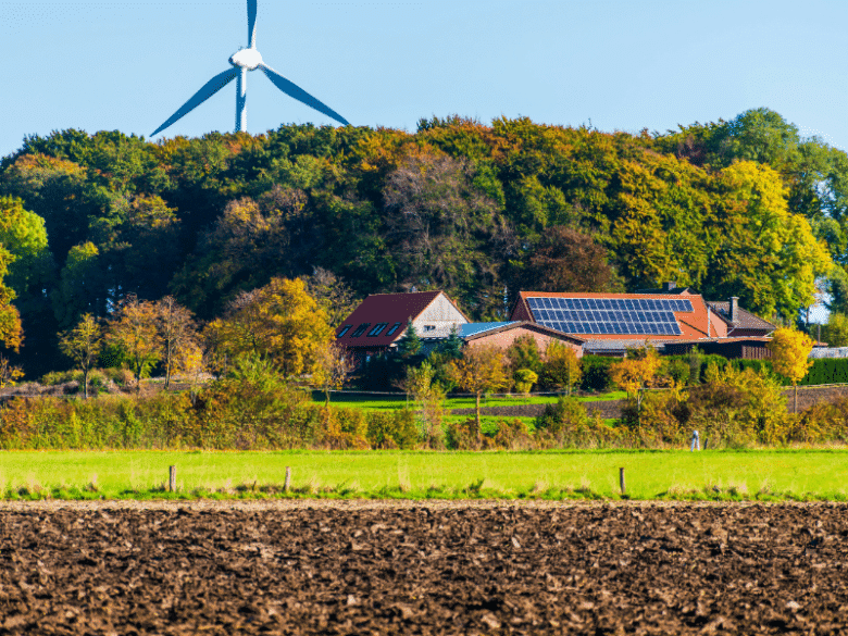 Agriculture landscape with solar rooftop and wind turbine in background.