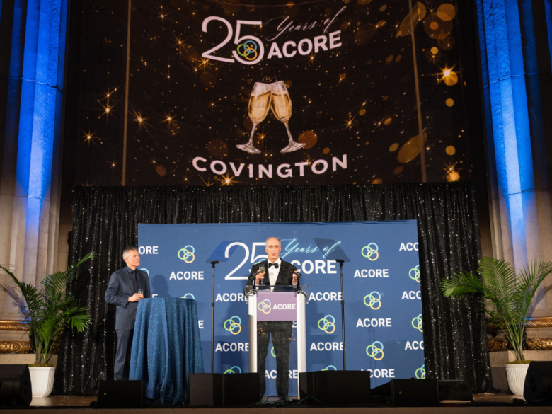 Speaker at the podium during ACORE’s 25th Anniversary Gala, with ACORE branding and Covington recognition projected above the stage.