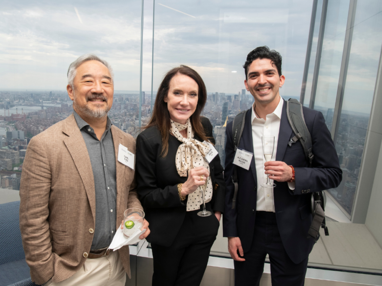 Three ACORE event attendees posing together in front of a New York City skyline.