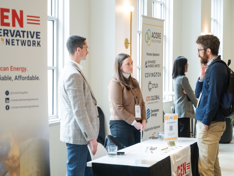 Attendees networking near sponsor displays and an exhibitor table at the ACORE Policy Forum.