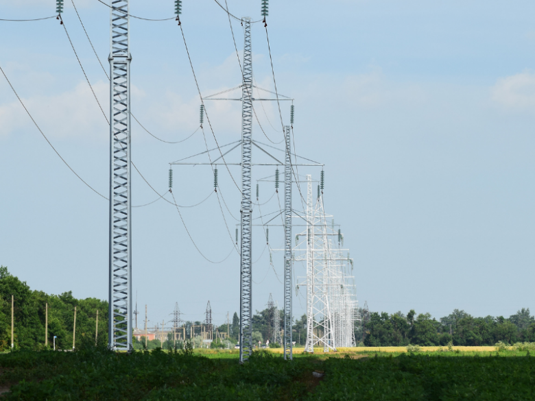 High-voltage electrical transmission towers and power lines extending across a landscape.