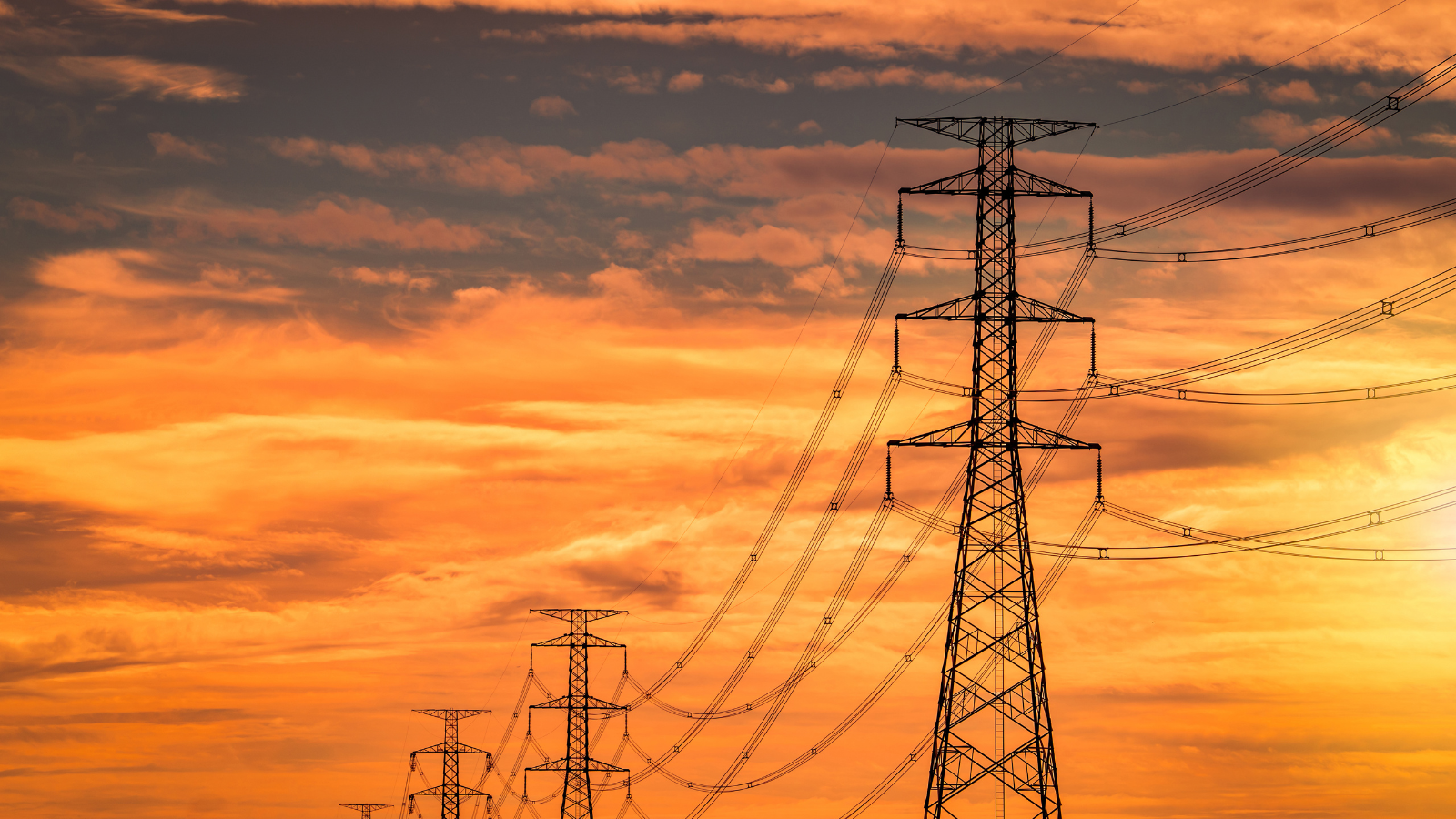 Transmission towers with a golden sunset in the background.